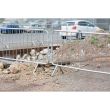 Multiple galvanised steel crowd barriers deployed on a gravel construction site, enclosing a hole in the ground.